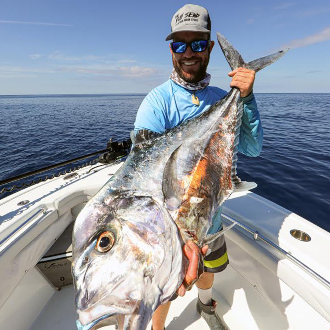 Captain Jason Stock showing off a Kingfish catch with some storm clouds in the background.